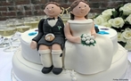 Um casal de bonecos de bolo sobre um belo bolo de casamento. <br/> <br/> Palavras-chave: casamento, instituição familiar, sociedade, cultura.