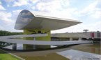 "O mais novo museu de Curitiba foi inaugurado em novembro de 2002 com o nome de Novo Museu e seguindo projeto de Oscar Niemeyer... O projeto de Oscar Niemeyer aproveitou as instalaes de uma antiga escola, que tambm era um projeto seu de 1967. A estrutura externa, que lembra um grande olho, impressiona pelas formas.  uma edificao, anexada  j existente, com 70 metros de comprimento, 30 de largura e cobertura parablica apoiada em uma torre de 21 metros de altura. Uma passagem subterrnea faz a ligao entre os dois prdios. <br/> <br/> Pretende-se implantar, nas instalaes do Museu Oscar Niemeyer, um programa de educao artstica, com oficinas para o pblico, atelis de restauro, centro de documentao e material de apoio para cursos e simpsios." <br/> <br/> Palavras-chave: cultura, indstria cultural, arte, artes plsticas.