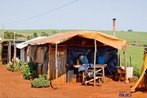 Barraca no acampamento tendo um latifndio de fundo <br/> Detalhe de acampamento do MST s margens de grandes latifndios de soja - 2008, na luta por assentamentos, reforma agrria e transformaes sociais. <br/> H 25 anos atrs, em Cascavel (PR), surgiu o MST unindo posseiros, atingidos por barragens, migrantes, meeiros, parceiros e pequenos agricultores. Desde sua fundao, o Movimento Sem Terra se organiza em torno de trs objetivos principais: Lutar pela terra; Lutar por Reforma Agrria; Lutar por uma sociedade mais justa e fraterna. <br/> <br/> Palavras-chave: Movimentos sociais, MST, acampamento, assentamento, direito, reforma agrria, trabalhadores rurais, camponeses, democracia, funo social da terra, cidadania, movimentos agrrios no Brasil.